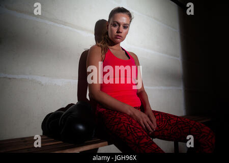 Portrait de sad woman relaxing on bench in fitness studio Banque D'Images