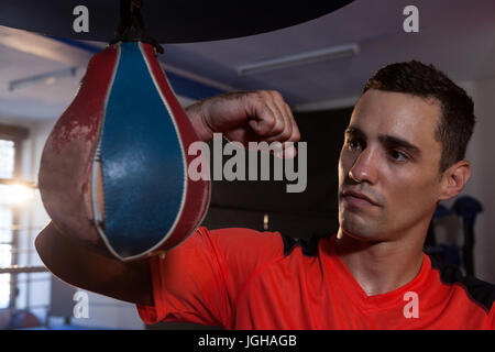 Male boxer pratiquer la boxe sac de frappe avec in fitness studio Banque D'Images