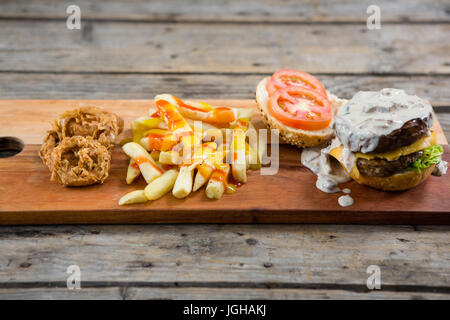 Portrait de Frites avec sauce en oignons et burger on cutting board Banque D'Images