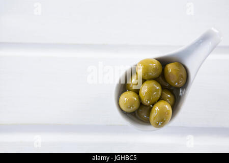 Close-up of olives vertes marinées dans une cuillère sur la table Banque D'Images