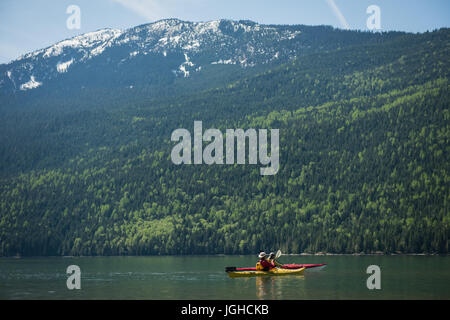 Couple de moyenne distance kayak dans le lac contre mountain Banque D'Images