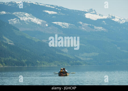 Vue à moyenne distance du couple tout en kayak dans le lac contre snowcapped mountain Banque D'Images