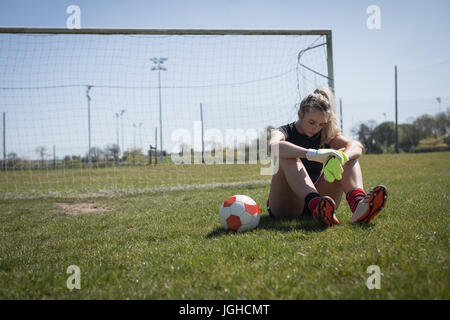 Toute la longueur du joueur de soccer féminin fatigués détente sur terrain de jeu Banque D'Images