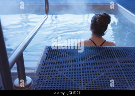 Vue arrière de la femme se détendre dans le bain à remous à la maison Banque D'Images