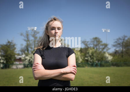 Portrait of female soccer player with arms crossed standing sur terrain de jeu Banque D'Images