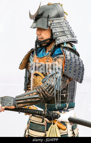 Le Japon, Tatsuno. Festival d'avril. Smiling man habillé en guerrier samouraï en armure complète, debout contre la toile blanche qui pose pour la photo. Banque D'Images