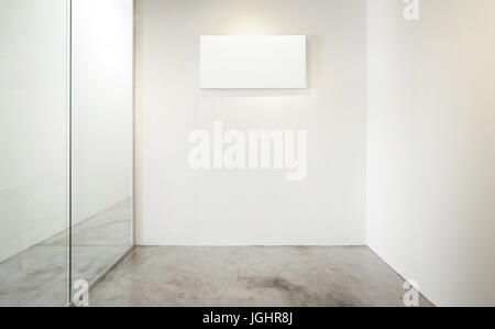 Bureau vide chambre, fenêtre en verre à gauche .Loft style intérieur , impression de toile blanche sur le centre mur blanc. sol en béton . Banque D'Images