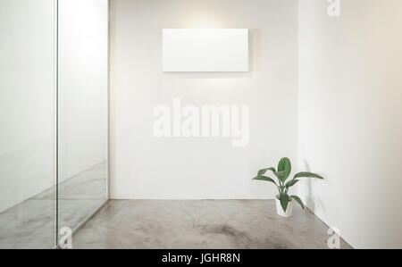 Bureau vide chambre, fenêtre en verre à gauche .plante verte à droite .Loft style intérieur , impression de toile blanche sur le mur blanc du centre. Le béton flo Banque D'Images