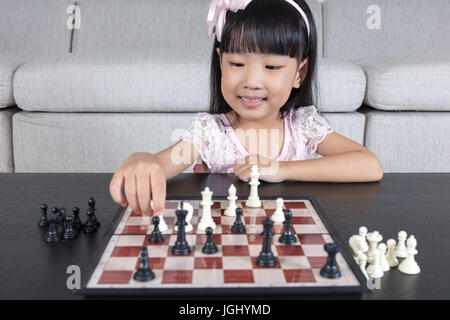 Chinois asiatique petite fille jouant aux échecs échecs dans la salle de séjour à la maison
