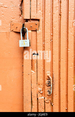 Seul le verrouillage d'un cadenas peint orange porte rustique en bois et métal Banque D'Images