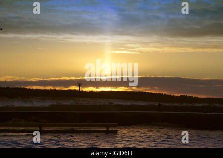 Pilier de lumière phénomène optique atmosphérique sur le coucher du soleil par la mer en hiver Banque D'Images