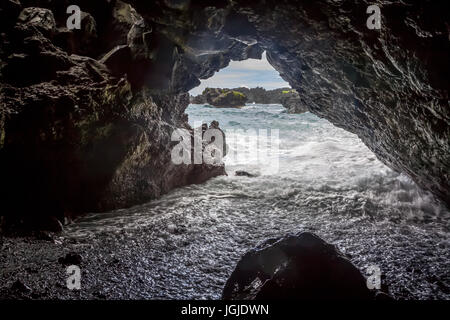 Vagues rouler dans une caverne à Waianapanapa Plage de sable noir près de Hana sur Maui, Hawaii, USA. Banque D'Images