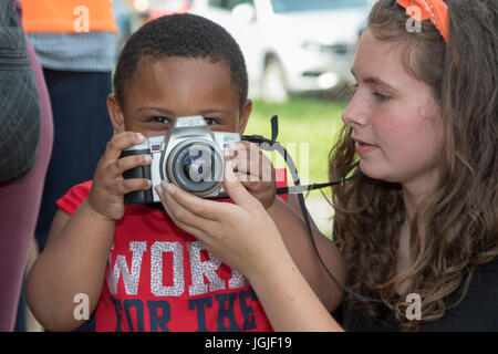 Detroit, Michigan - une fille aide un jeune garçon apprendre à utiliser un appareil photo. Banque D'Images