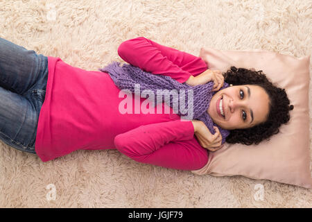 Femme aux cheveux bouclés court est allongé sur le tapis. Elle sourit et arracher l'appareil photo. Banque D'Images