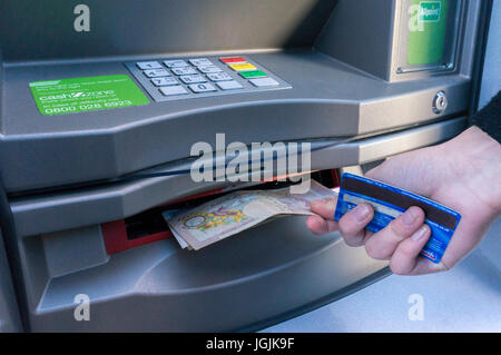 A woman's hand holding, une carte de crédit ou de débit tout en prenant dix livres sterling note, d'un distributeur distributeur automatique de billets. Londres, Angleterre, Royaume-Uni. Banque D'Images