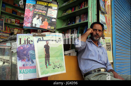 Srinagar, au Cachemire. 08 juillet, 2017. Photo de burhan wani est scène à news boutique de papier comme un commerçant parle sur son téléphone mobile, lorsque le couvre-feu comme aujourd'hui les autorités.Des restrictions imposées strict couvre-feu comme restrictions cachemire pour maintenir la loi et l'ordre que les accolades de la vallée pour le premier anniversaire de la mort de Hizbul Mujahideen 'commander' Burhan Wani . Credit : Sofi suhail/Alamy Live News Banque D'Images