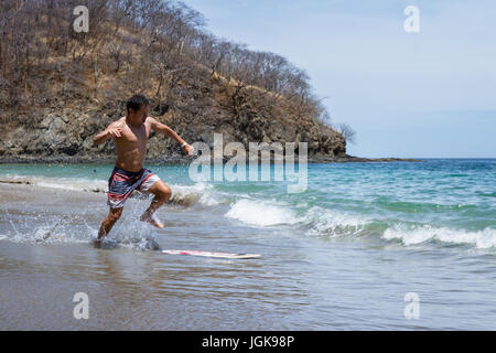 Jeune homme d'embarquement écrémé à Playa Calzon de Pobre, Costa Rica sur une belle journée ensoleillée. Banque D'Images