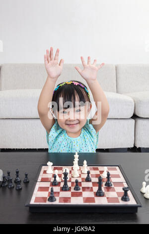 Chinois asiatique petite fille jouant aux échecs échecs dans la salle de séjour à la maison
