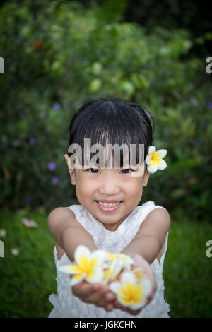 Chinois asiatique little girl holding Flowers in jardin extérieur sur la journée Banque D'Images