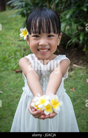 Chinois asiatique little girl holding Flowers in jardin extérieur sur la journée Banque D'Images