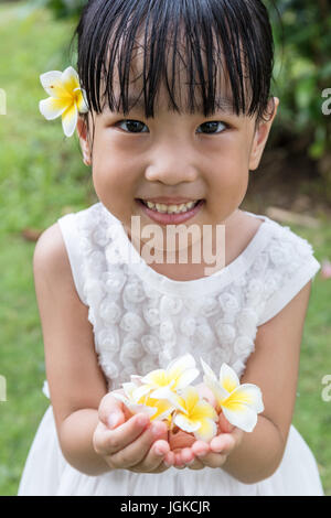 Chinois asiatique little girl holding Flowers in jardin extérieur sur la journée Banque D'Images