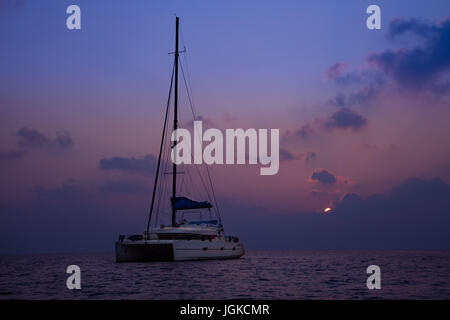 Ancrage Catamaran sur l'océan sombre dans la lumière au coucher du soleil, les Maldives, l'océan Indien Banque D'Images