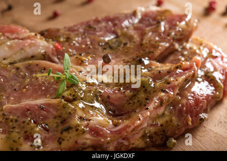 La viande de porc cru mariné prêt à être mis sur le grill avec le poivre et le thym Banque D'Images