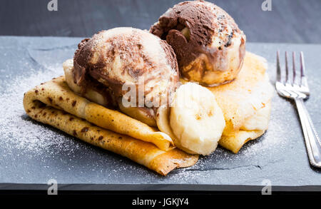 De délicieuses crêpes farcies avec une sauce au chocolat, avec des boules de glace sur le dessus, servant un plat savoureux dessert élégant Banque D'Images