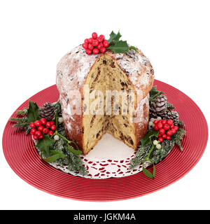 Panettone au chocolat gâteau de Noël avec le houx, le gui, Ivy, sapin, pommes de pin sur une plaque rouge isolé sur fond blanc. Banque D'Images