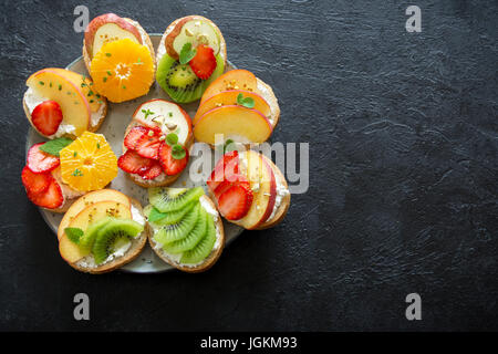 Dessert de fruits des sandwiches à base de ricotta. Délicieux petit déjeuner sain des toasts avec du fromage à la crème, fruits frais biologiques et de baies, herbes, noix et Banque D'Images