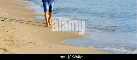 Homme marchant sur la plage de sable fin. Closeup détail de l'homme pieds et sable doré sur la plage Banque D'Images