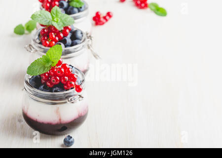 Maison traditionnelle panna cotta dessert italien avec sauce aux baies dans des bocaux en verre, décoré avec les baies fraîches sur fond de bois blanc Banque D'Images