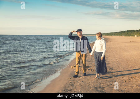 Couple de personnes âgées ayant promenade romantique sur la plage au coucher du soleil Banque D'Images