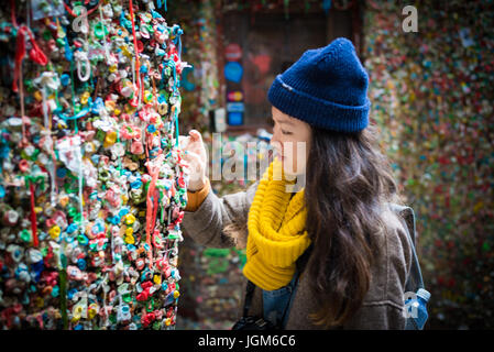 Fille collant un morceau de bubblegum mâché sur le mur de la gomme de Seattle. Banque D'Images