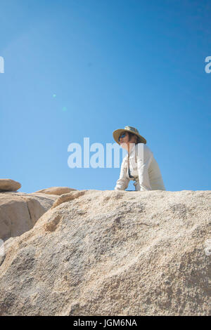 Girl climbing en haut d'un gros rocher à Joshua Tree National Park Banque D'Images