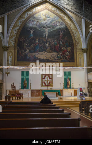 Femme solitaire à Sainte Thérèse Eglise catholique qui a masses en anglais, chinois et espagnol à Manhattan dans le Lower East Side. Banque D'Images