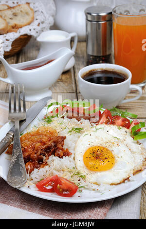 Le petit déjeuner - riz bouilli avec des œufs brouillés, bacon, les tranches de tomate et les verts Banque D'Images