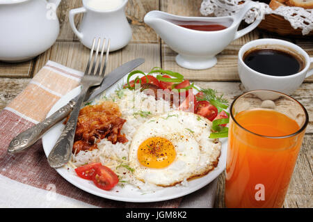 Le petit déjeuner - riz bouilli avec des œufs brouillés, bacon, les tranches de tomate et les verts Banque D'Images