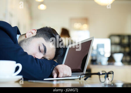 Analyste jeunes dormir sur le clavier de l'ordinateur portable en cafe Banque D'Images