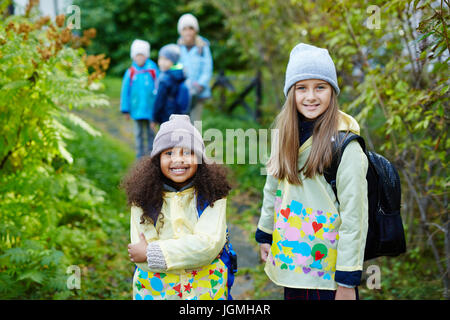 Portrait de deux écolières avec des sacs, l'un d'entre eux Solidarité, pose, smiling at camera sur le chemin de l'école de jour d'automne lumineux avec gro Banque D'Images