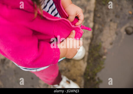 Un bambin zipping son blouson mains seulement. Banque D'Images