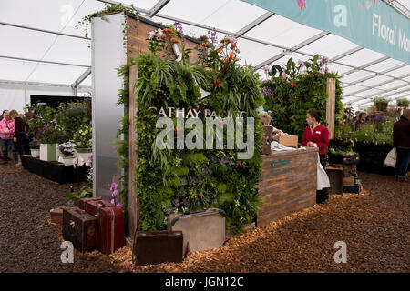 Personnes, plantes exotiques & valises rétro par Cathay Pacific trade support - Chatsworth RHS Flower Show marquee, Chatsworth House, Derbyshire, Angleterre, Royaume-Uni. Banque D'Images