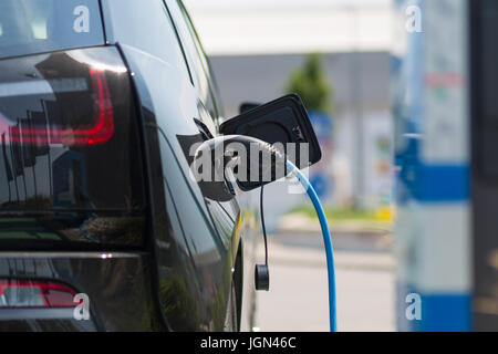 Bloc d'alimentation branché sur une voiture électrique en cours de charge. Banque D'Images