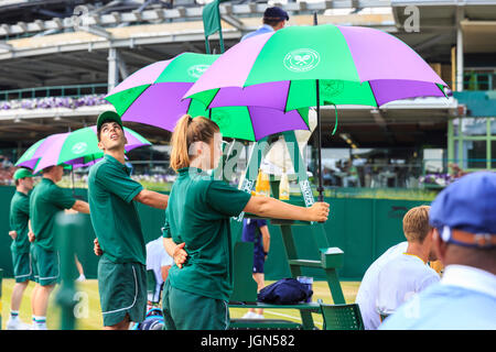 Préposés à l'audience de Wimbledon jusqu'à l'ombre des parasols les joueurs du soleil sur une journée ensoleillée et particulièrement chaud au Wimbledon Tennis Championships 201 Banque D'Images