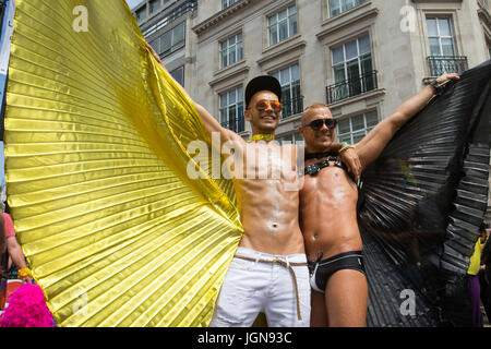 Deux gars s'étirer leurs ailes noir et or à la marche de la fierté à Londres Banque D'Images