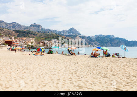 GIARDINI NAXOS, ITALIE - 28 juin 2017 : Les vacanciers sur la plage urbaine en Giardini-Naxos ville et vue de la ville de Taormina, sur l'île. Giardini Naxos est station Banque D'Images