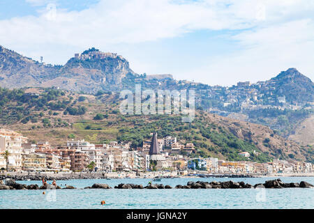 GIARDINI NAXOS, ITALIE - 28 juin 2017 : les gens sur front de plage près de la ville de Giardini-Naxos et vue de la ville de Taormina, sur l'île. Giardini Naxos est la mer Banque D'Images