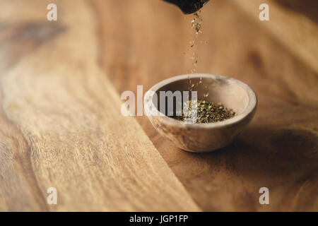 Provence séchées herb mix tomber dans un bol en bois pour l'assaisonnement sur table Banque D'Images