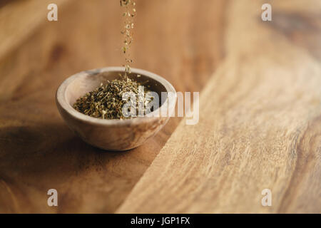 Provence séchées herb mix tomber dans un bol en bois pour l'assaisonnement sur table Banque D'Images