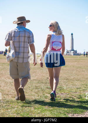 Un homme et une femme marchant sur un champ avec la dame en exécutant les vêtements et une "race for life' t-shirt Banque D'Images